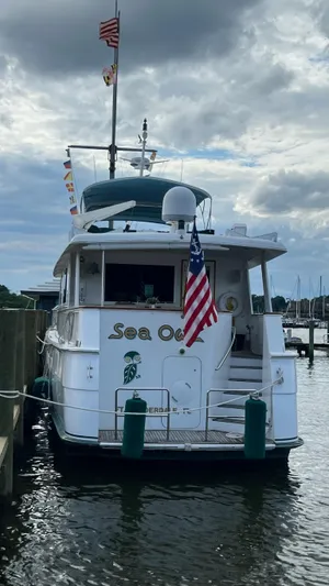 Sea Owl Yacht Photos Pics 1987 Hatteras Motoryacht docked, displaying flags and American flag, under cloudy sky.