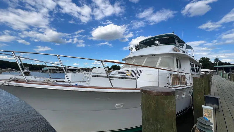 Sea Owl Yacht Photos Pics 1987 Hatteras Motoryacht docked under a vibrant blue sky with scattered clouds.