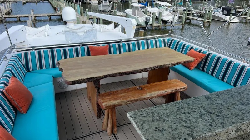 Sea Owl Yacht Photos Pics 1987 Hatteras Motoryacht deck with rustic wooden table, striped seating, and marina view.