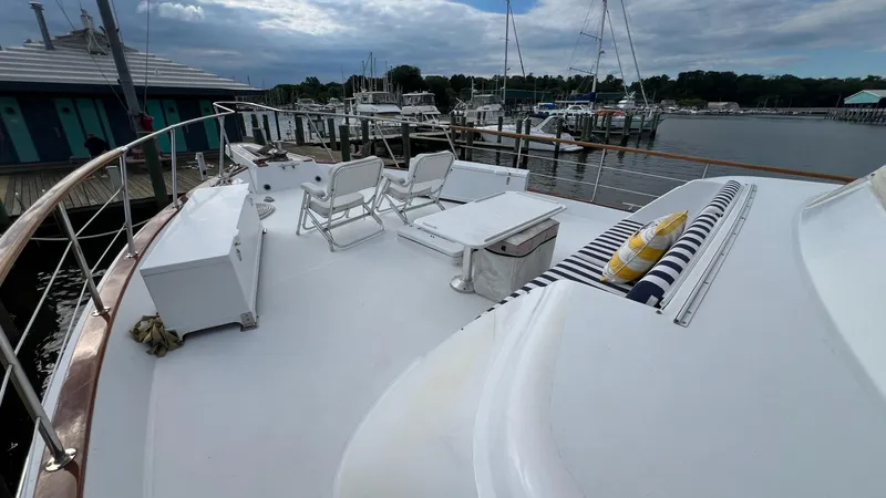 Sea Owl Yacht Photos Pics 1987 Hatteras Motoryacht deck with chairs and striped cushions, docked at a marina.