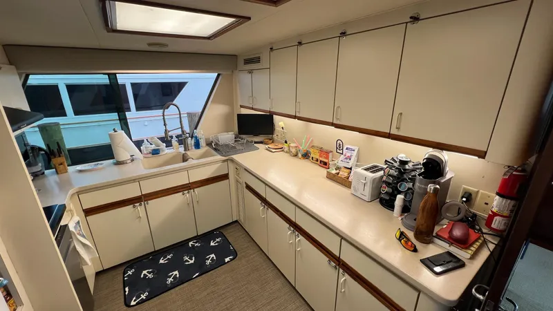 Sea Owl Yacht Photos Pics 1987 Hatteras Motoryacht kitchen with white cabinets, appliances, and nautical-themed decor.