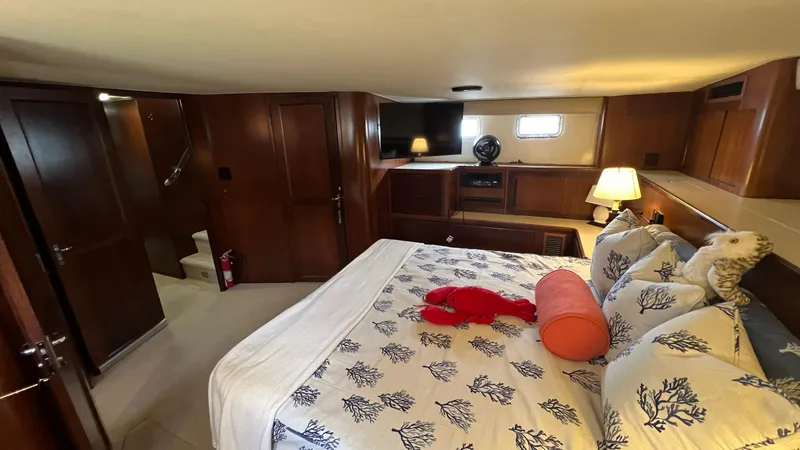 Sea Owl Yacht Photos Pics Luxurious bedroom interior of a 1987 Hatteras Motoryacht with elegant bedding and wooden furnishings.