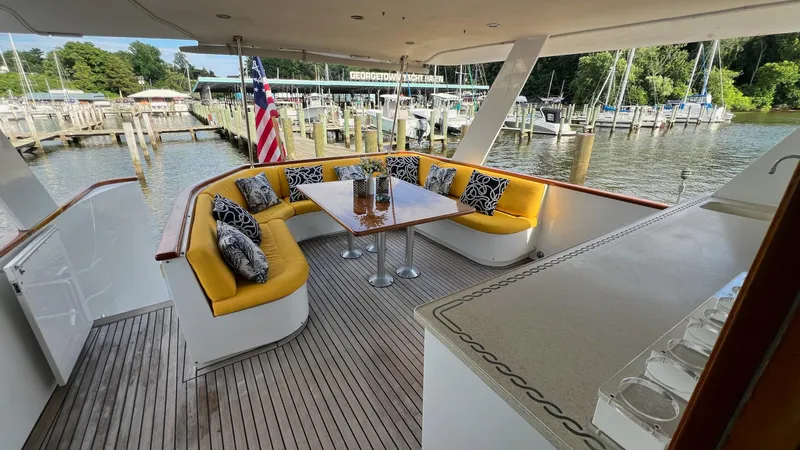 Sea Owl Yacht Photos Pics 1987 Hatteras Motoryacht deck with yellow seating, table, and marina view.