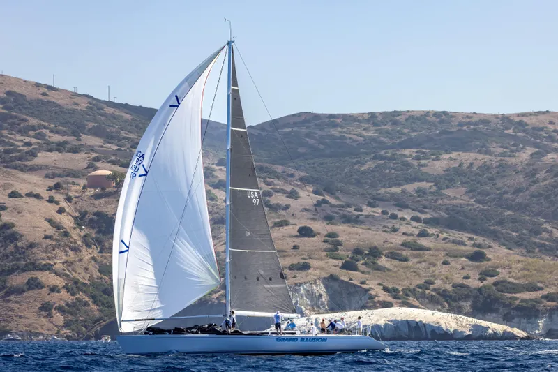 Grand Illusion Yacht Photos Pics Sailing yacht Santa Cruz 70, 1986 model, gliding near rocky coastline under clear skies.