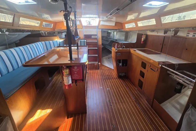 Grand Illusion Yacht Photos Pics Interior of 1986 Santa Cruz 70 yacht with wooden flooring and blue-striped seating.