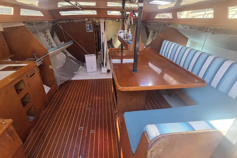 Grand Illusion Yacht Photos Pics Interior of a 1986 Santa Cruz 70 sailboat with wooden furnishings and striped seating.