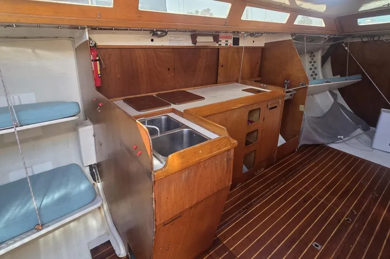 Grand Illusion Yacht Photos Pics 1986 Santa Cruz 70 yacht interior with wooden cabinetry, sink, and seating area.