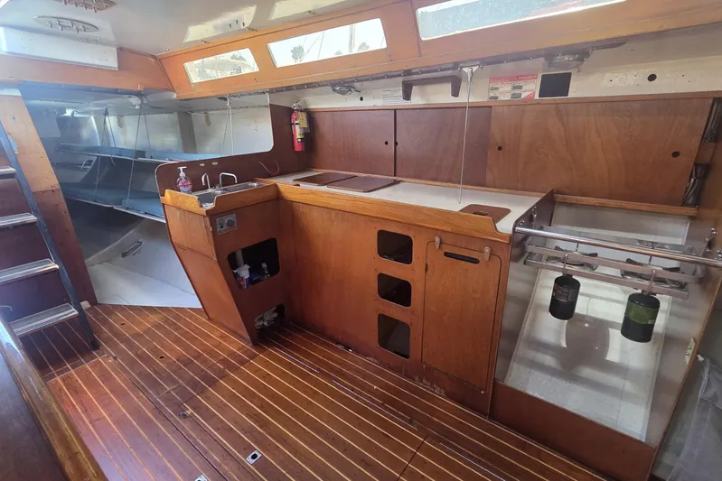Grand Illusion Yacht Photos Pics Interior of 1986 Santa Cruz 70 sailboat with wooden cabinetry and compact kitchen area.