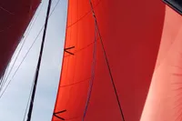 Red sail of 2018 Outremer 4X catamaran against blue sky.