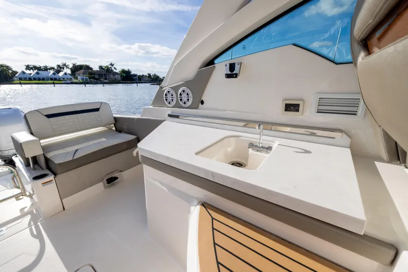 34 Tiara 2022 Yacht Photos Pics 2022 Tiara 34 LX boat interior with seating and sink, overlooking waterfront homes.
