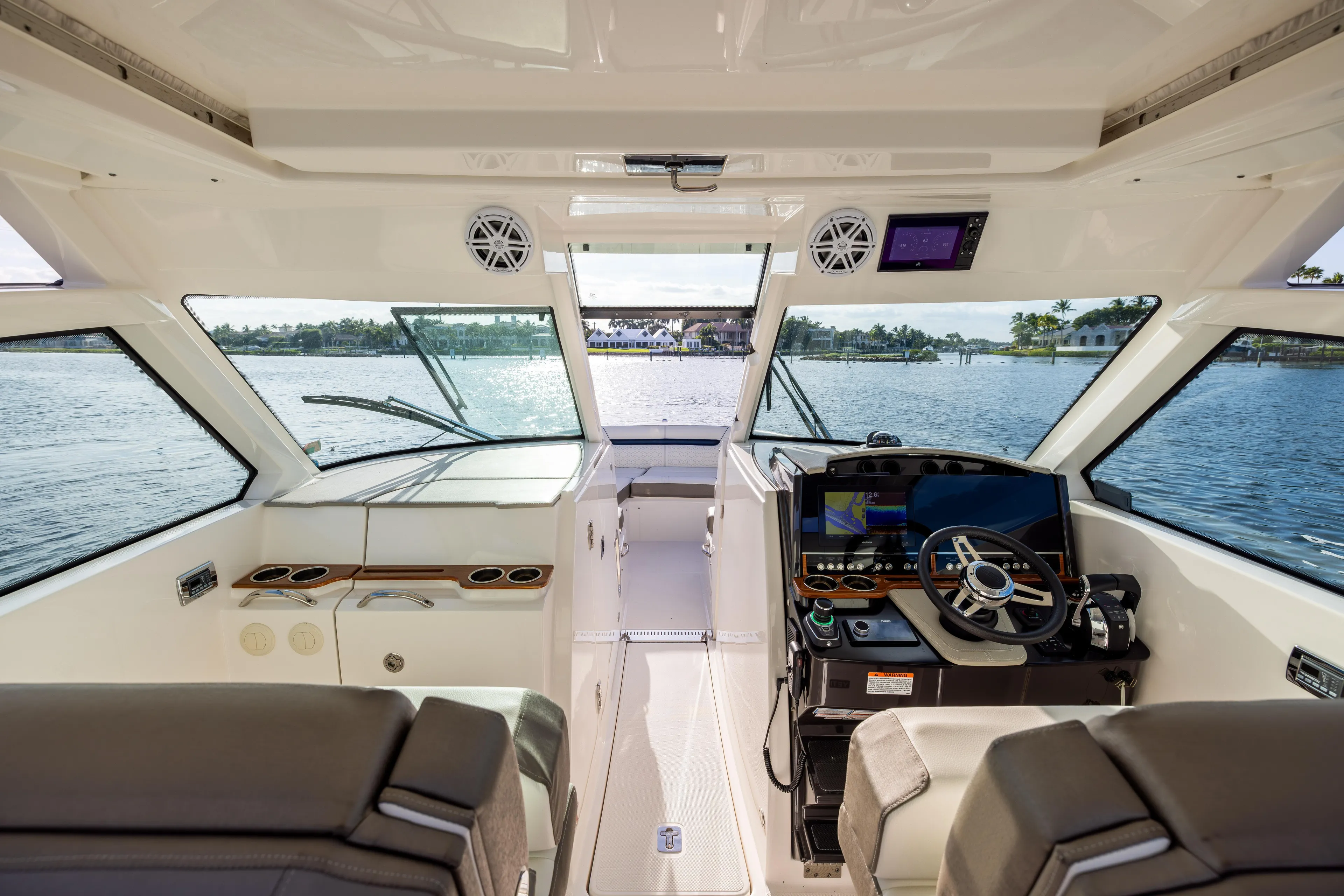 34 Tiara 2022 Yacht Photos Pics Interior view of 2022 Tiara 34 LX boat cockpit with modern controls and waterfront scenery.