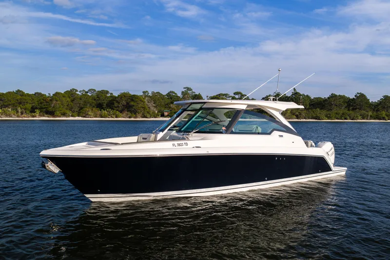 34 Tiara 2022 Yacht Photos Pics 2022 Tiara 34 LX boat on calm water with scenic forest backdrop.