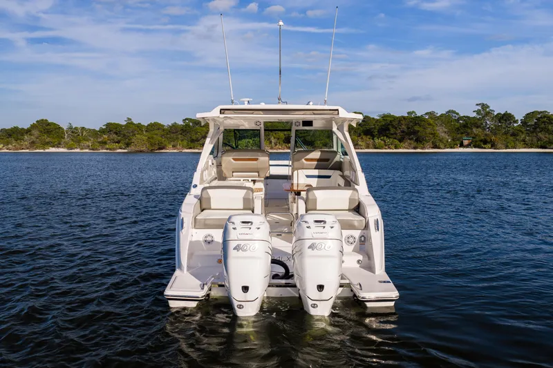 34 Tiara 2022 Yacht Photos Pics 2022 Tiara 34 LX boat on water with twin engines, scenic shoreline background.