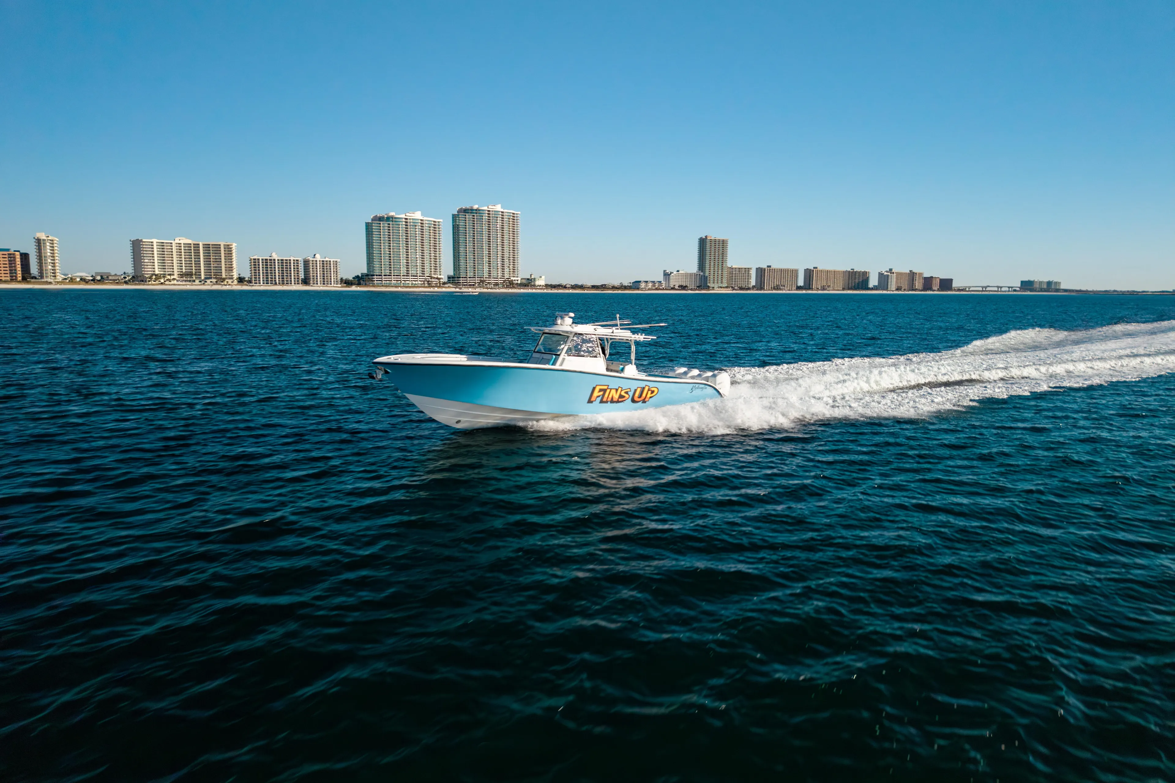 Fins Up Yacht Photos Pics 2017 Yellowfin 42 Offshore boat cruising on ocean near city skyline.