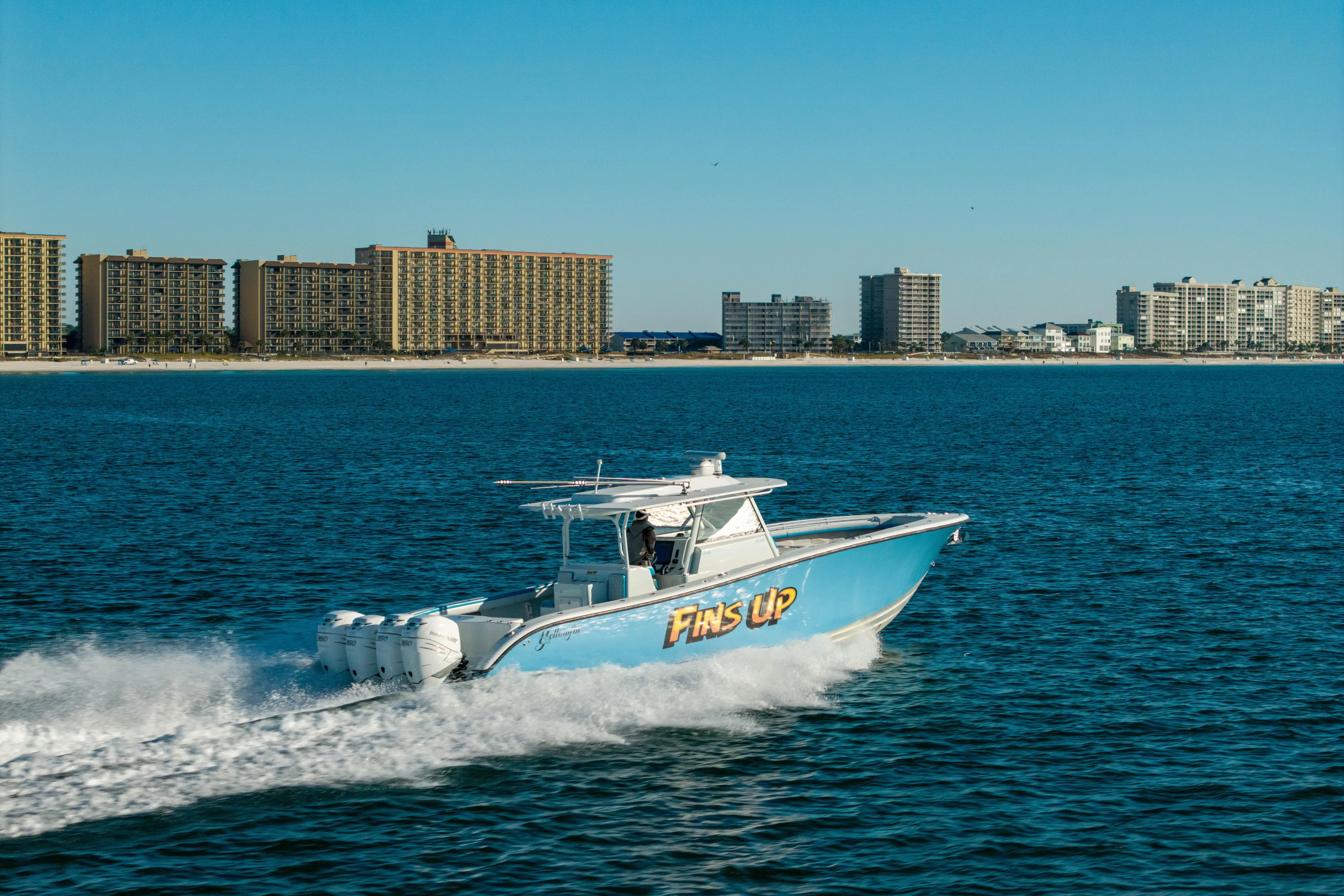 Fins Up Yacht Photos Pics 2017 Yellowfin 42 Offshore boat cruising near coastal city skyline.