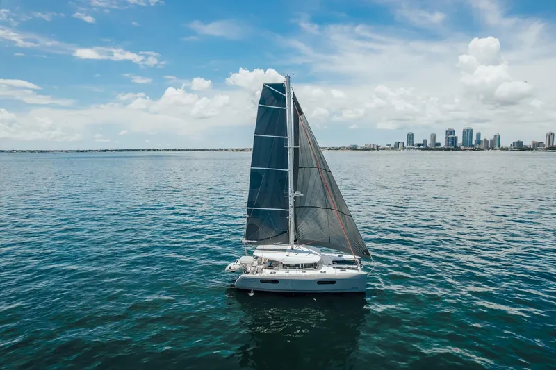 27 Reasons Yacht Photos Pics Sailing catamaran Excess 12, 2020 model, on open water with city skyline background.