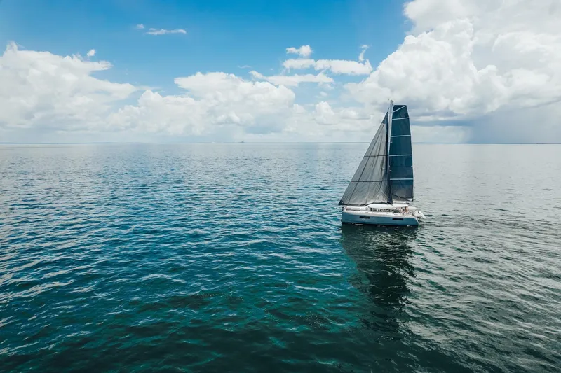 27 Reasons Yacht Photos Pics Sailboat "Excess 12" 2020 model on open sea under blue sky and clouds.