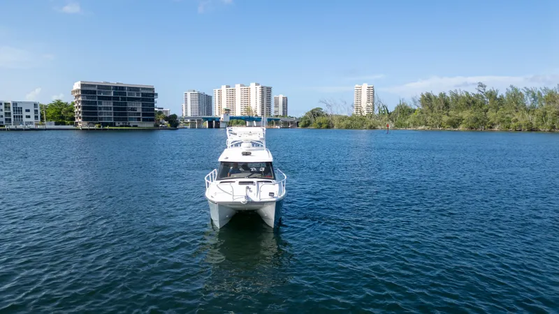 Transcendent Yacht Photos Pics 2023 ArrowCat Flybridge Dual Helm boat on calm water with cityscape background.