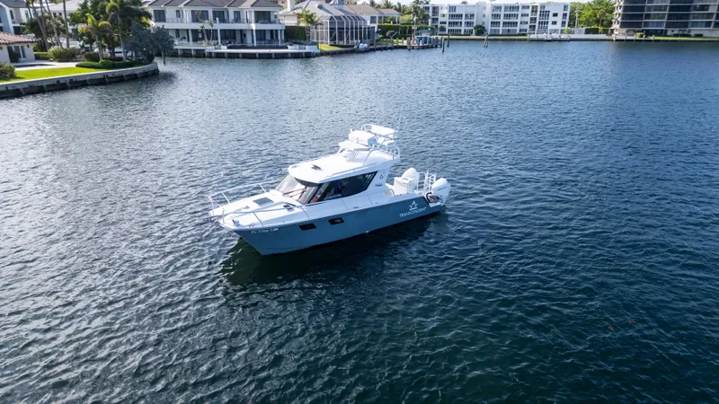 Transcendent Yacht Photos Pics 2023 ArrowCat Flybridge Dual Helm boat on calm water near waterfront homes.