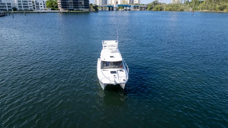 Transcendent Yacht Photos Pics 2023 ArrowCat Flybridge Dual Helm boat on calm water near urban buildings.