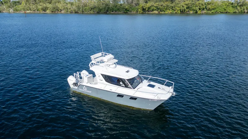 Transcendent Yacht Photos Pics 2023 ArrowCat Flybridge Dual Helm boat on calm water, surrounded by lush greenery.