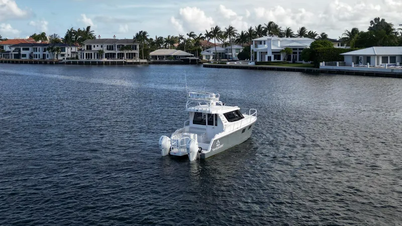 Transcendent Yacht Photos Pics 2023 ArrowCat Flybridge Dual Helm boat on a serene waterfront with luxury homes.