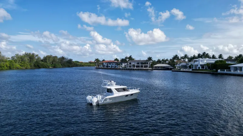 Transcendent Yacht Photos Pics 2023 ArrowCat Flybridge Dual Helm boat on a serene waterfront with luxury homes.