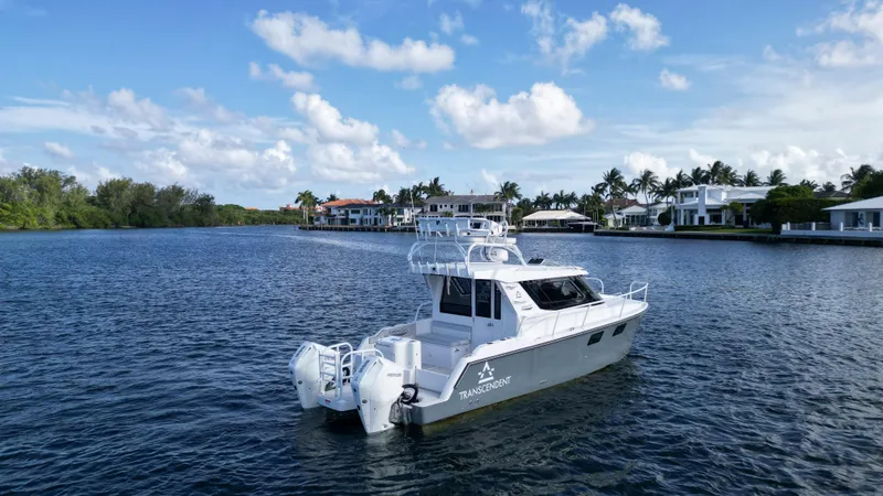 Transcendent Yacht Photos Pics 2023 ArrowCat Flybridge Dual Helm boat on a serene waterway with luxury homes.