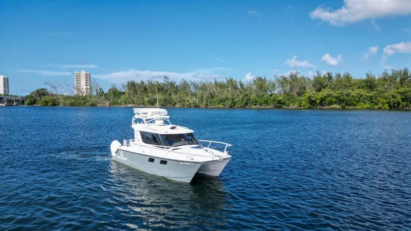 Transcendent Yacht Photos Pics 2023 ArrowCat Flybridge Dual Helm cruising on a serene lake under a clear blue sky.