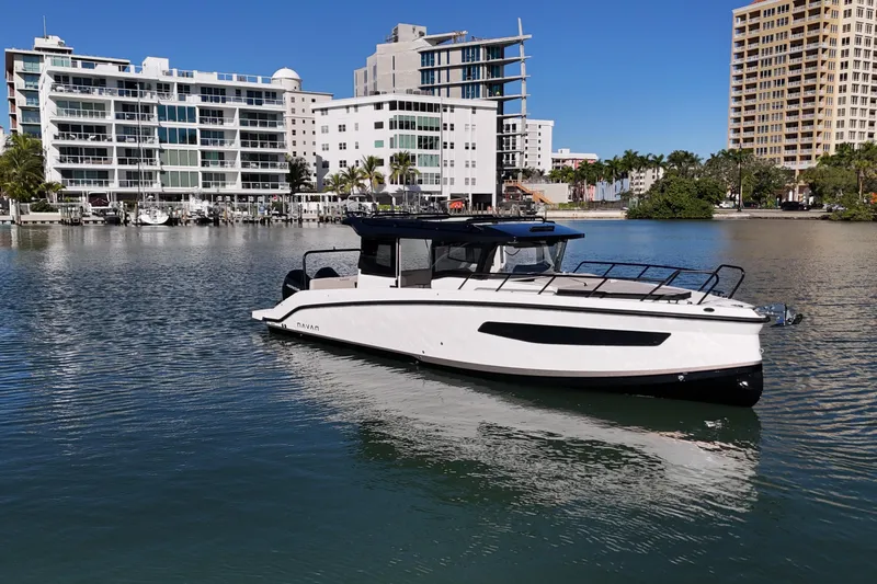  Yacht Photos Pics 2026 Navan C30 boat on calm water with modern buildings in the background.