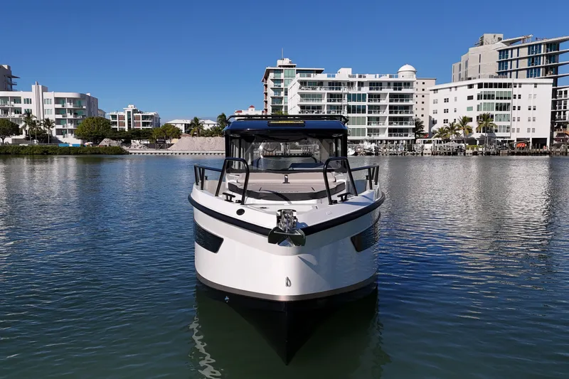  Yacht Photos Pics Front view of 2026 Navan C30 boat on calm water with modern buildings in background.