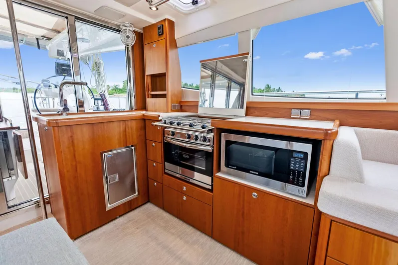 Southwind Yacht Photos Pics Modern kitchen area in 2021 Moody 45 DS yacht with stove, microwave, and wooden cabinetry.