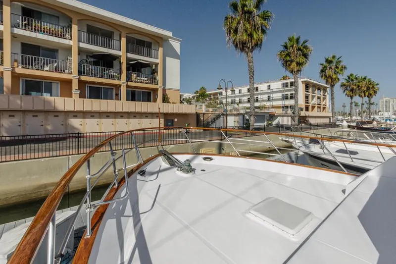 Betelgeuse Yacht Photos Pics 1988 DeFever 53 POC yacht docked near waterfront buildings and palm trees.