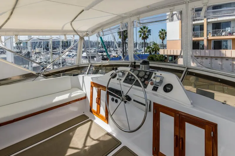 Betelgeuse Yacht Photos Pics 1988 DeFever 53 POC yacht helm with marina view, featuring steering wheel and controls.