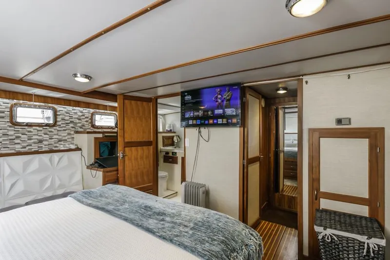 Betelgeuse Yacht Photos Pics 1988 DeFever 53 POC yacht bedroom with TV, wood accents, and modern decor.