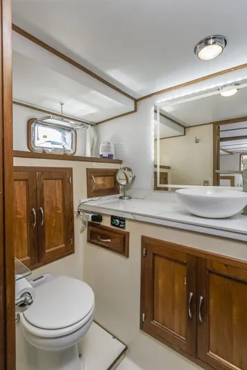 Betelgeuse Yacht Photos Pics 1988 DeFever 53 POC yacht bathroom with wooden cabinets and modern fixtures.