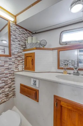 Betelgeuse Yacht Photos Pics 1988 DeFever 53 POC yacht bathroom with modern tile backsplash and wooden cabinetry.
