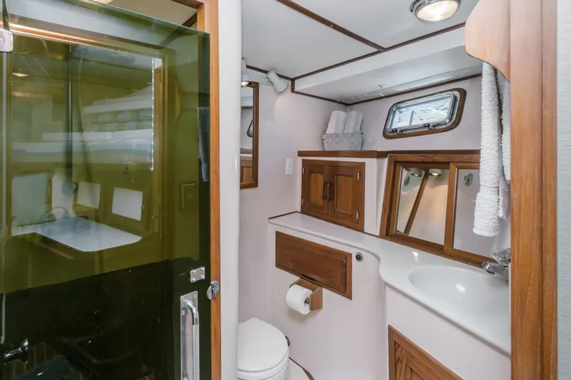 Betelgeuse Yacht Photos Pics 1988 DeFever 53 POC yacht bathroom with shower, sink, and wooden cabinetry.