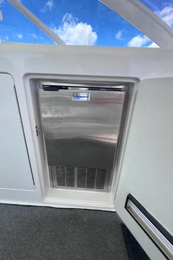 Sugar Bear Yacht Photos Pics Stainless steel fridge on 2001 Cabo 45 Express boat under blue sky.