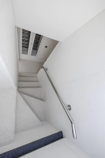 Skyfall Yacht Photos Pics Staircase inside 2008 Sunseeker Predator 108 yacht, featuring sleek white design and handrail.