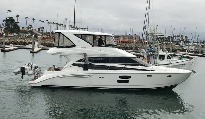 Mother Ship Yacht Photos Pics 2011 Meridian 441 Sedan Bridge yacht in marina, overcast sky, palm trees in background.