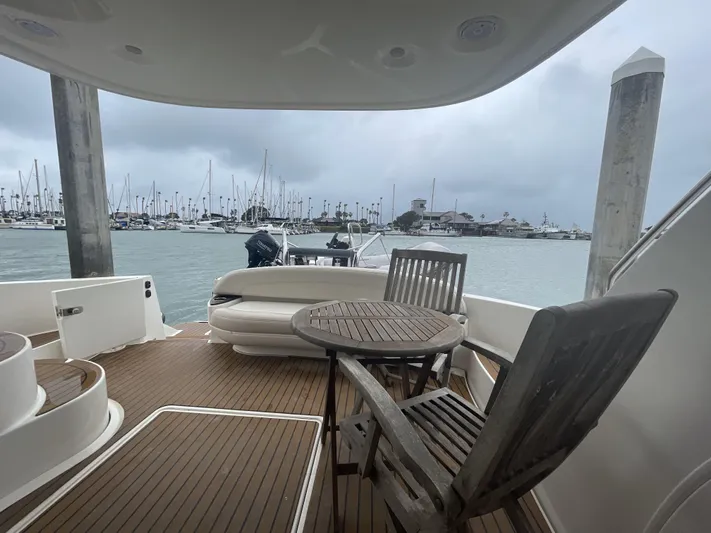 Mother Ship Yacht Photos Pics 2011 Meridian 441 Sedan Bridge yacht deck with wooden chairs, table, and marina view.