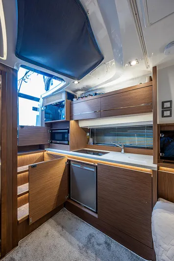 Brama Sole Yacht Photos Pics Modern kitchen interior of 2022 Jeanneau Leader 12.5 yacht with wood cabinetry and appliances.