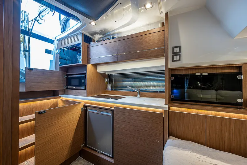 Brama Sole Yacht Photos Pics Modern kitchen interior of 2022 Jeanneau Leader 12.5 yacht with wood cabinetry and appliances.
