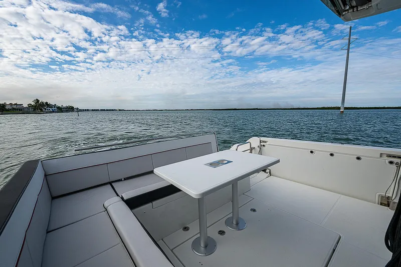 Brama Sole Yacht Photos Pics 2022 Jeanneau Leader 12.5 boat deck with seating and table, overlooking serene waters.