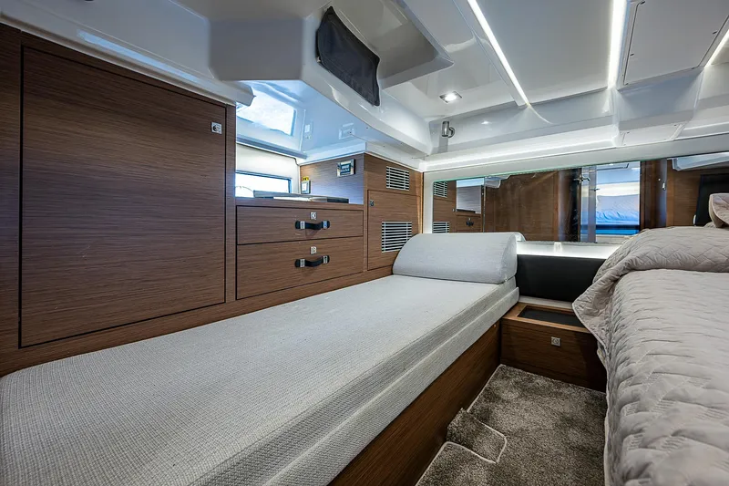 Brama Sole Yacht Photos Pics Luxurious interior of 2022 Jeanneau Leader 12.5 yacht with modern wood finish and comfortable bedding.