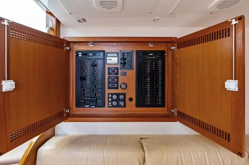 Ebtide Yacht Photos Pics Electrical panel inside 2006 Cabo 45 Express boat, featuring wooden cabinetry and control switches.