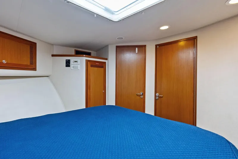 Ebtide Yacht Photos Pics Interior cabin of 2006 Cabo 45 Express yacht with blue bedding and wooden doors.
