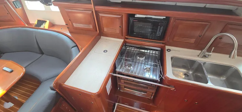 Royce Yacht Photos Pics Interior of 2007 Beneteau 423 yacht kitchen with stove, sink, and seating area.