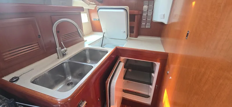 Royce Yacht Photos Pics Galley of 2007 Beneteau 423 yacht with sink, fridge, and wooden cabinetry.
